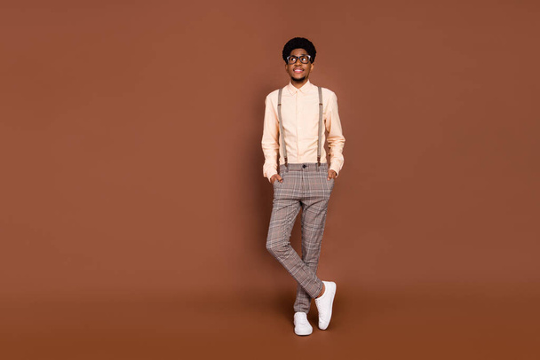 Full length body size view of attractive cheerful minded guy holding hands in pockets deciding isolated over brown color background - Fotoğraf, Görsel