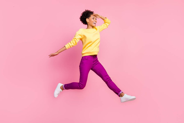 Photo of excited attractive lady wear yellow pullover jumping high looking far away empty space isolated pink color background - 写真・画像