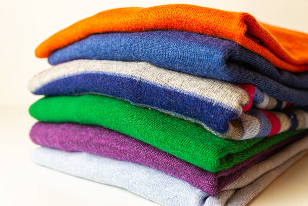 Στοίβα φθινοπωρινών πουλόβερ διαφόρων χρωμάτων, τοποθετημένα το ένα πάνω στο άλλο. Ζεστά ρούχα και η άφιξη του φθινοπώρου και του πρώτου κρύου.  - Φωτογραφία, εικόνα