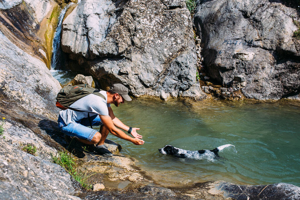Propriétaire mâle de chien d'épagneul marchant contre les montagnes et les chutes d'eau fond. - Photo, image