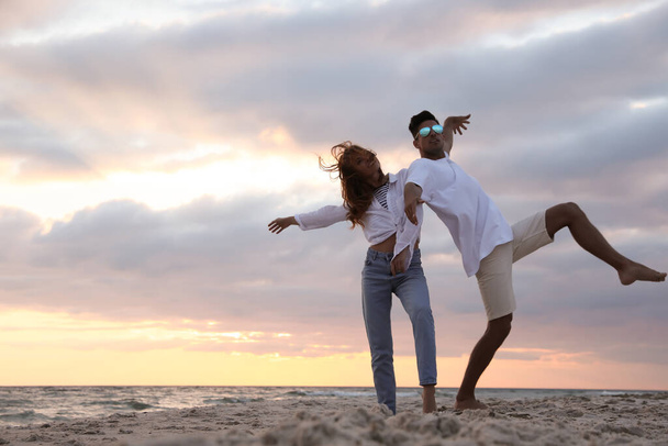 Happy couple dancing on beach at sunset - Foto, Imagen