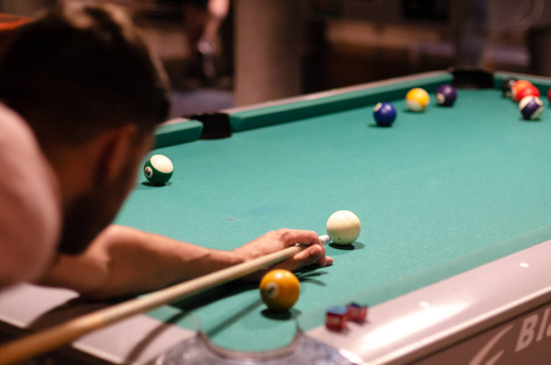 Young man playing pool in a bar. man shooting game of pool or billiards. Pool game in process - Fotoğraf, Görsel