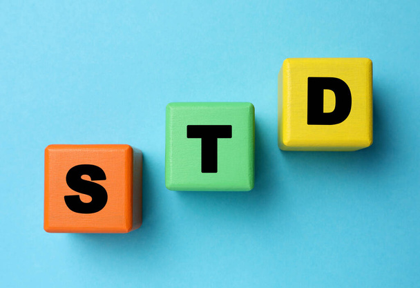 Abbreviation STD made with cubes on light blue background, flat lay - Fotó, kép