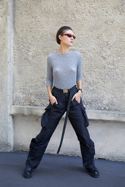 MILAN, ITALY - SEPTEMBER 24, 2021: Woman with black cargo trousers and pink and black sunglasses before Prada fashion show, Milan Fashion Week street style - Zdjęcie, obraz
