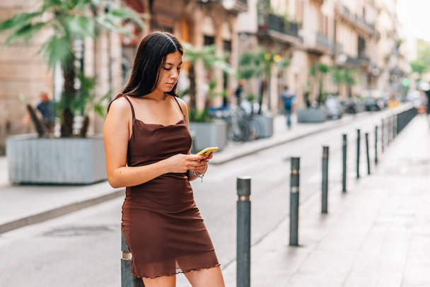 nuori kiinalainen nainen käyttää hänen puhelimensa kaduilla Barcelona - Valokuva, kuva