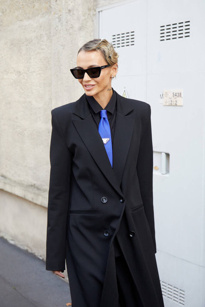 MILAN, ITALY - SEPTEMBER 24, 2021: Woman with black jacket and blue Prada tie before Prada fashion show, Milan Fashion Week street style - Foto, imagen