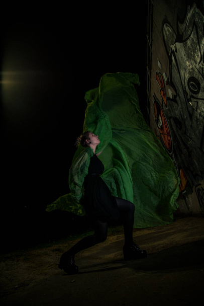 Girl posing in green draping on dark background - 写真・画像