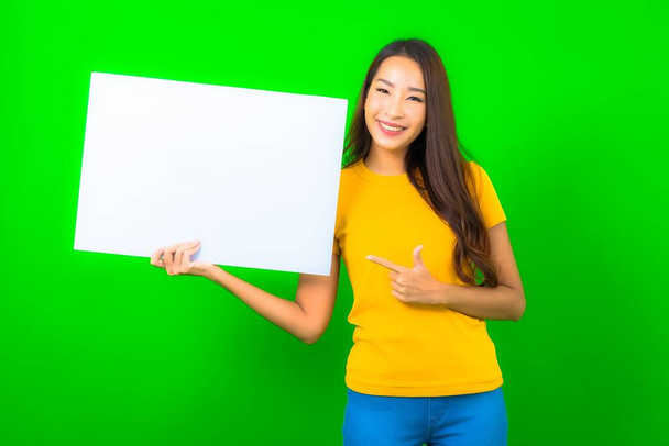 Портрет красива молода азіатка показує білий порожній рекламний щит на фоні зеленого кольору
 - Фото, зображення
