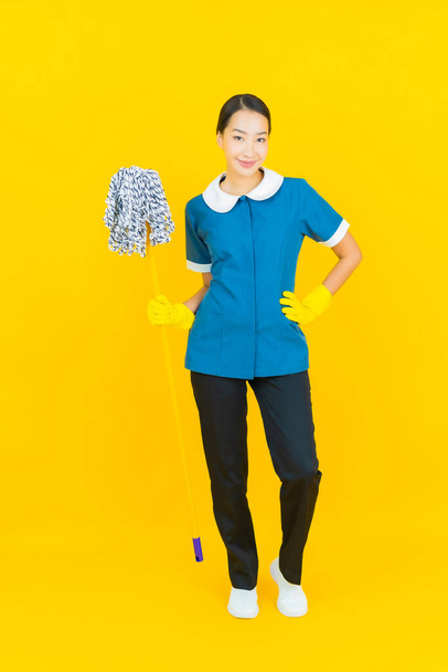 Portrait beautiful young asian woman maid and housekeeping smile with action on yellow color background - Foto, immagini