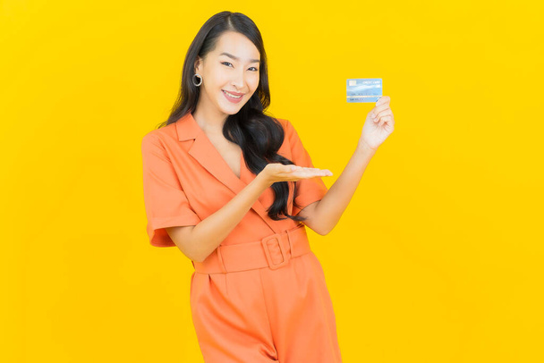 Portret piękna młoda azjatycka kobieta uśmiech z karty kredytowej na żółtym tle - Zdjęcie, obraz