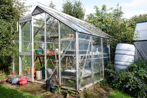 Glass greenhouse and water butt in back garden - Foto, imagen