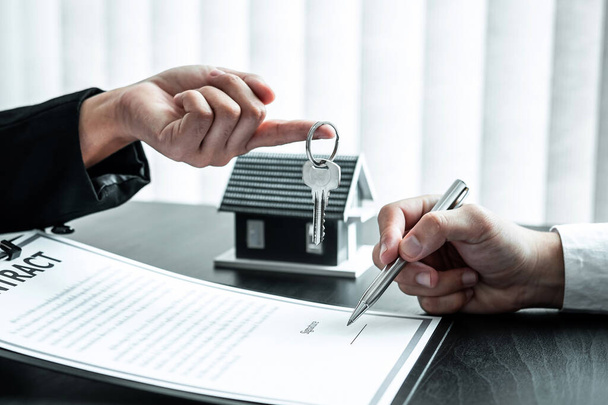 Az ingatlanügynök lakáshitelt nyújt, és kulcsokat küld az ügyfélnek, miután aláírta a szerződést a bérházzal.. - Fotó, kép
