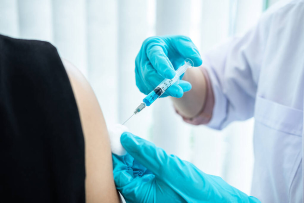 Doctor making a vaccination into patient with needle getting immune vaccine at arm for flu shot, coronavirus protective of epidemic. - Photo, Image