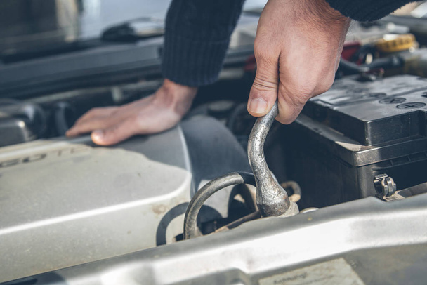 Mechanic hand checking and fixing a broken car in car service garage - Foto, imagen