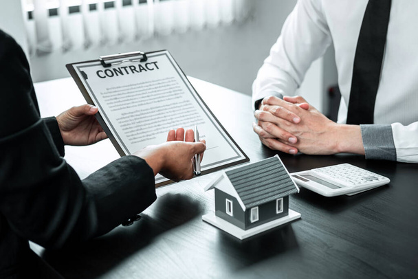 Agent nieruchomości prezentuje klientowi kredyt mieszkaniowy oraz omawia przy podpisywaniu decyzji formularz umowy, koncepcję Home Insurance i inwestycji nieruchomościowych. - Zdjęcie, obraz