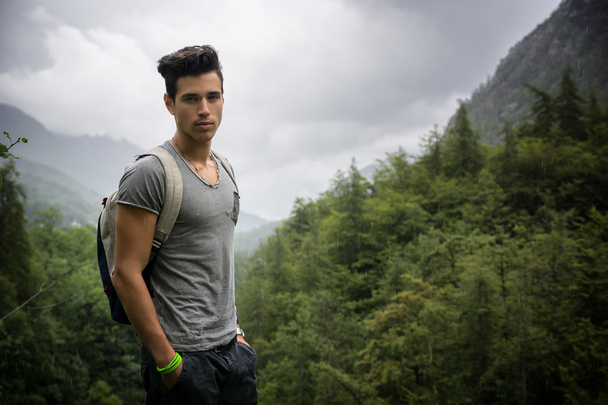 Handsome athletic young man with backpack in mountains - Фото, изображение