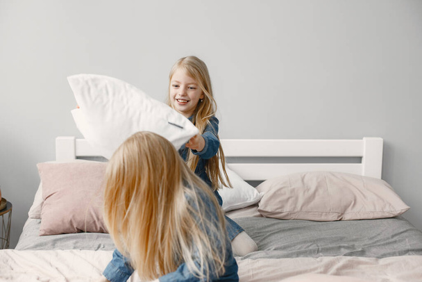 Two cute little sisters playing on bed with pillows - Fotoğraf, Görsel