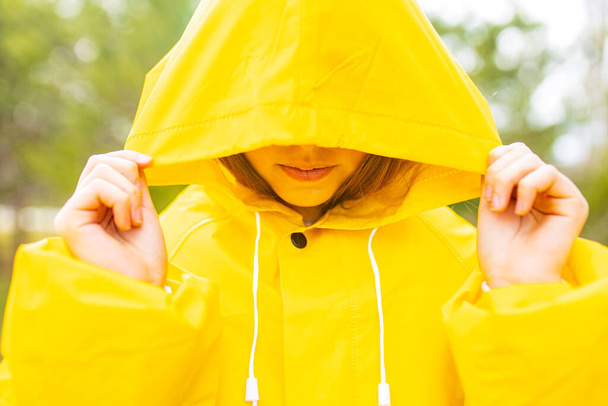 smiling teenage girl wearing raincoat outdoors in rainy day . - Zdjęcie, obraz