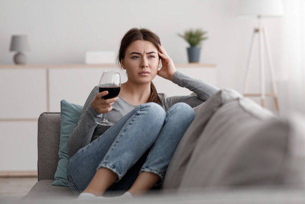 Triste jeune femme caucasienne frustrée avec un verre de vin souffrant de dépression, de stress et de surmenage à la maison - Photo, image