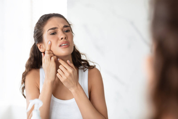 Desperate Lady Squeezing Pimple On Face Near Mirror In Bathroom - Valokuva, kuva
