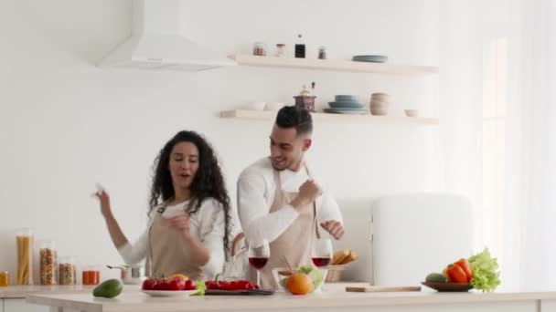 Happy arabic spouses having fun dancing while cooking in kitchen - Footage, Video