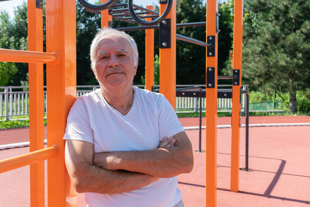 Ejercicios al aire libre seguros para adultos mayores Hombre mayor Verano masculino, entrenamiento en la calle Actividad de fuerza física en el Parque de Calistenia - Foto, imagen