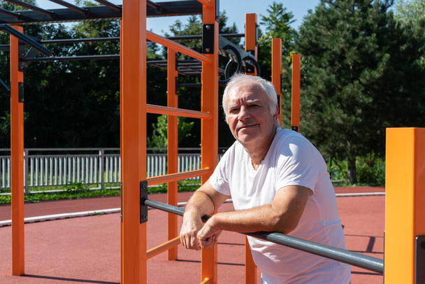 Bezpečná venkovní cvičení pro starší dospělé seniory mužské léto, pouliční cvičení fyzická síla aktivita v parku Calisthenics - Fotografie, Obrázek