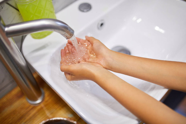 Kislány kezet mos szappannal otthon a fürdőszobában. - Fotó, kép