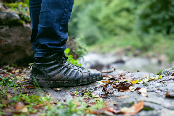 Sonbaharda kirli ayakkabılı bir adam ayakta duruyor. - Fotoğraf, Görsel