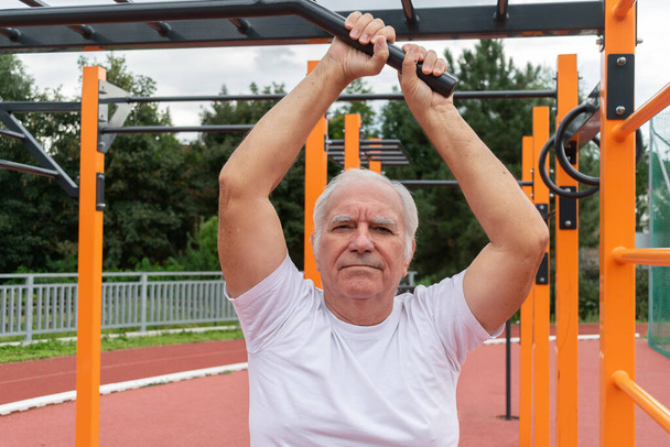 Bezpieczne ćwiczenia na świeżym powietrzu dla starszych dorosłych seniorów mężczyzna lato, trening uliczny wysiłek fizyczny w Calisthenics Park - Zdjęcie, obraz