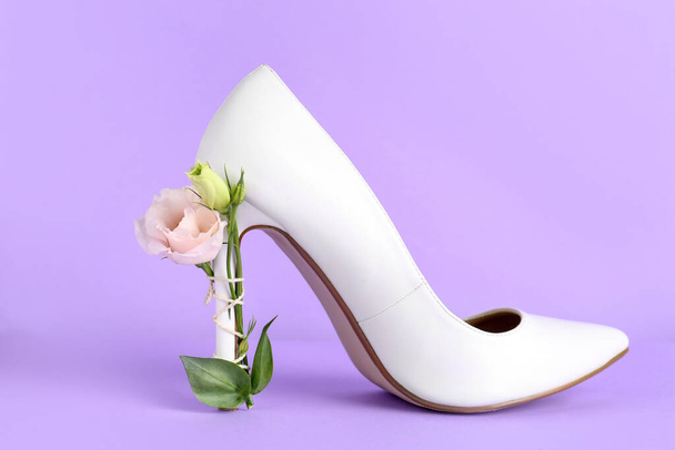 Stylish women's high heeled shoe with beautiful flower on violet background - Fotó, kép