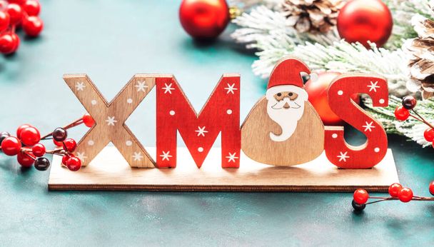 Синій різдвяний або новорічний фон з червоними різдвяними кульками, ягодами, ялиновими гілками, сосновими шишками та написом Xmas
 - Фото, зображення
