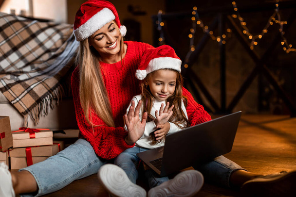 Happy festive woman and daughter using pc making videocall - Foto, Imagem