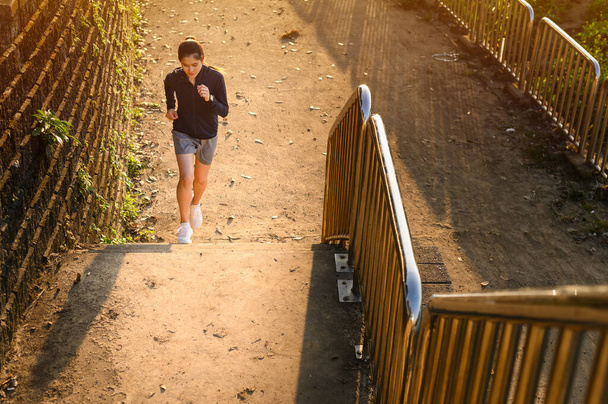 Retrato de una joven corredora de fitness entrenándose subiendo escaleras en la calle urbana. Uphill running puede mejorar la velocidad media de carrera y su longitud de paso mayor beneficio. - Foto, imagen