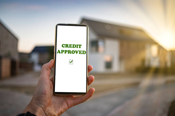 real estate credit approved on phone newly built house in the background - Photo, Image