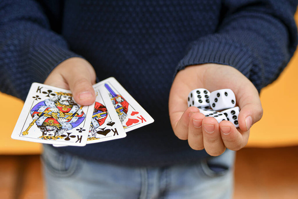 Kaarten en dobbelstenen spelen in de hand van een persoon die biedt om te gokken in een casino. - Foto, afbeelding