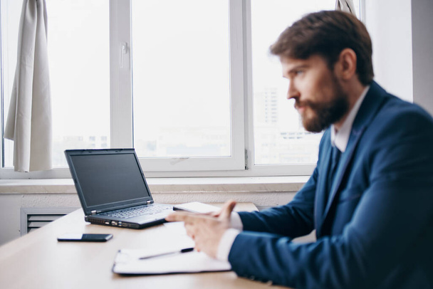 man met baard zittend aan een bureau voor een laptop - Foto, afbeelding