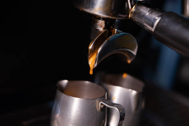 black coffee is pouring from professional coffee machine. coffee making by barista. dark loft coffee shop - Foto, Bild
