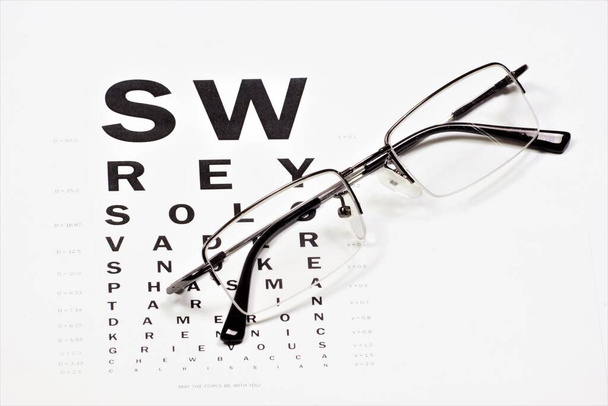 Очки с диоптриями для коррекции зрения на диаграмме проверки зрения. - Фото, изображение