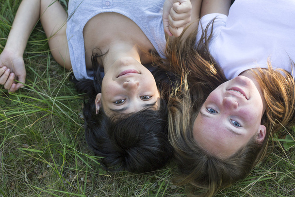 zwei junge Mädchen liegen auf Gras. - Foto, Bild