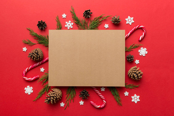 Flat lay composizione natalizia. quadrata Carta bianca, rami di pino, decorazioni natalizie su sfondo colorato. Vista dall'alto, copia lo spazio per il testo. - Foto, immagini