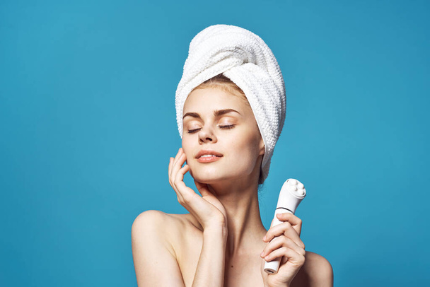krásná žena s ručníkem na hlavě masážní v ruce péče o pleť - Fotografie, Obrázek