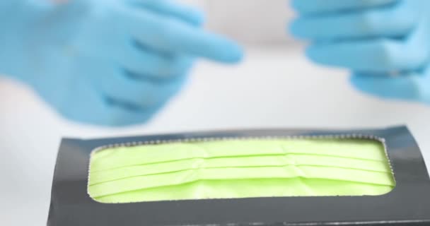 Doctor in beschermende medische rubberen handschoenen trekken medisch masker uit doos 4k film - Video