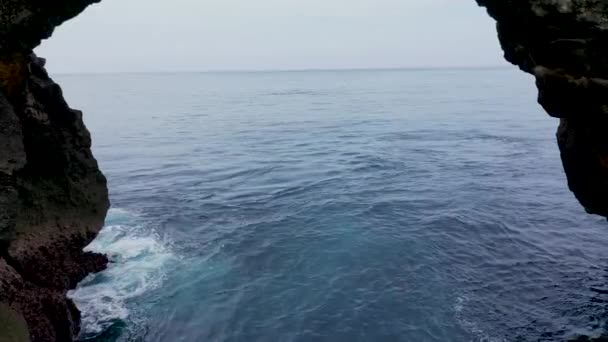 Ik zag een rotsboog. Arches geproduceerd door oceaanerosie op de Indische oceaan, Nusa Penida, Bali. golven storten neer - Video
