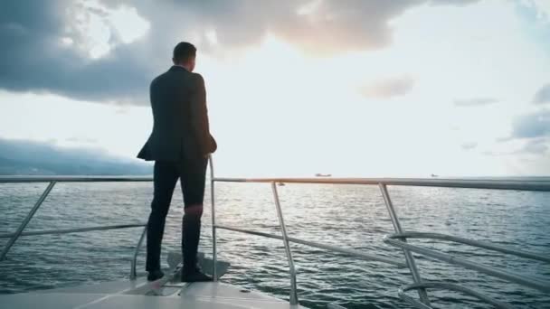Homem de sucesso em um terno navegando em um iate no mar para o horizonte. 4K tiro - Filmagem, Vídeo
