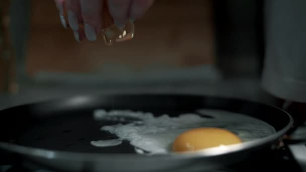 Chica rompe un huevo tortilla en una sartén caliente primer plano en cámara lenta - Imágenes, Vídeo