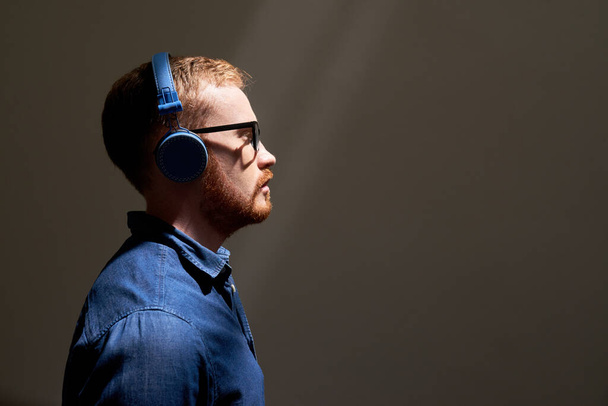 Σοβαρός άντρας με μπλε ακουστικά - Φωτογραφία, εικόνα