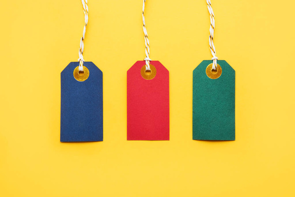 Colorful blank sale tags on a bright yellow background. Black Friday and sales concept. Top view, copy space - Foto, Bild