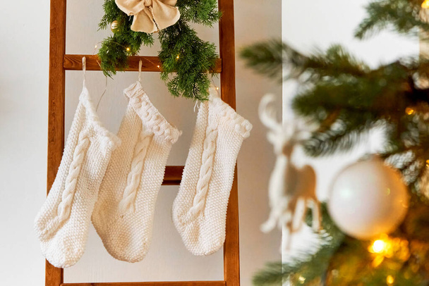 Decorazioni di Natale festive di una camera leggera con un albero di Natale e calzini a maglia per i regali di Babbo Natale. - Foto, immagini