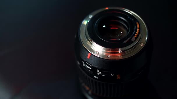 Soporte de lente de cámara profesional aislado sobre fondo negro con destellos de luz de neón dorado - Imágenes, Vídeo